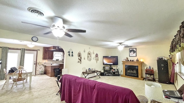 96848 S 4510th Rd, Vian, OK 74962 - living room with a ceiling fan, carpet, a textured ceiling, arched walkways, and a fireplace