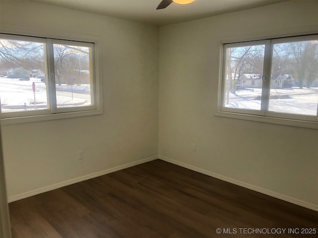 spare room with ceiling fan, dark wood-type flooring, and baseboards