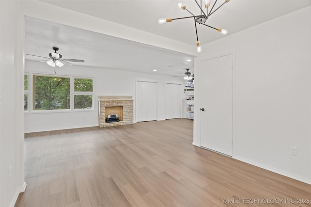 501 W 17th St, Pawhuska, OK 74056 - unfurnished living room featuring light wood finished floors, a chandelier, a fireplace, ceiling fan, and baseboards