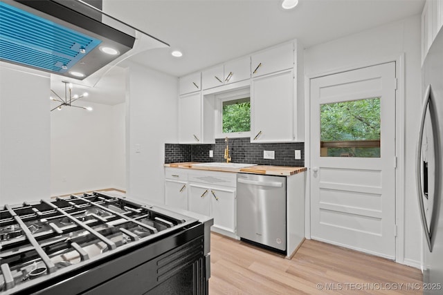 501 W 17th St, Pawhuska, OK 74056 - kitchen with stainless steel appliances, butcher block countertops, exhaust hood, light wood-type flooring, and a sink