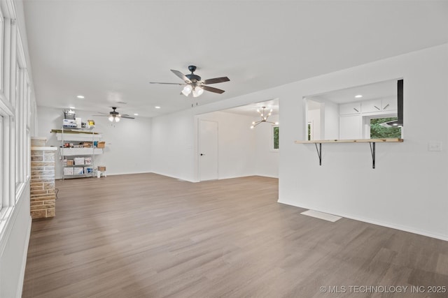 501 W 17th St, Pawhuska, OK 74056 - unfurnished living room featuring a brick fireplace, a ceiling fan, wood finished floors, recessed lighting, and a chandelier