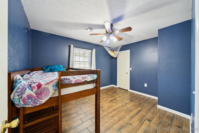 bedroom featuring ceiling fan, dark hardwood / wood-style floors, and a textured ceiling