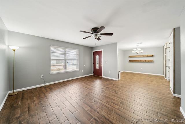 unfurnished living room with ceiling fan with notable chandelier and dark hardwood / wood-style flooring