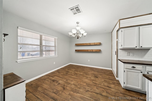 unfurnished dining area with an inviting chandelier and dark hardwood / wood-style floors