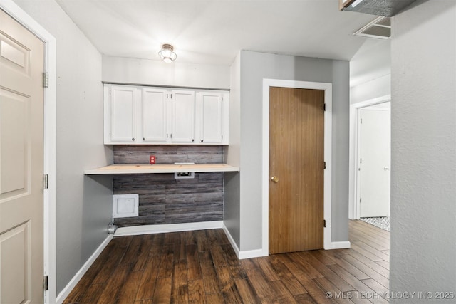 bar featuring dark hardwood / wood-style flooring, white cabinetry, and decorative backsplash