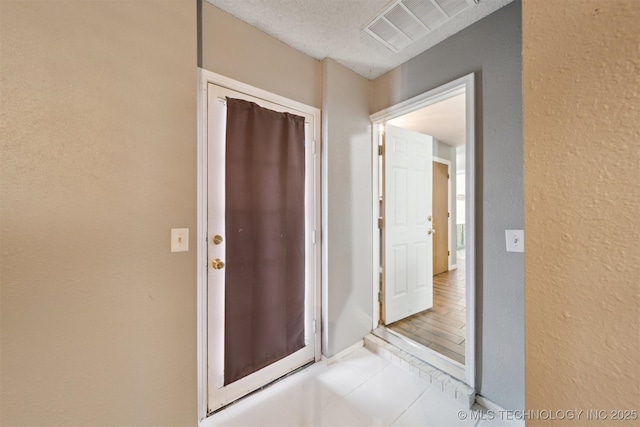 hallway featuring light tile patterned flooring and a textured ceiling