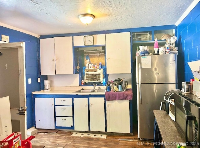 kitchen featuring white cabinetry, sink, dark wood-type flooring, and stainless steel fridge