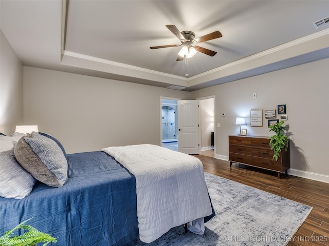 bedroom featuring dark hardwood / wood-style floors, ceiling fan, ornamental molding, and a tray ceiling