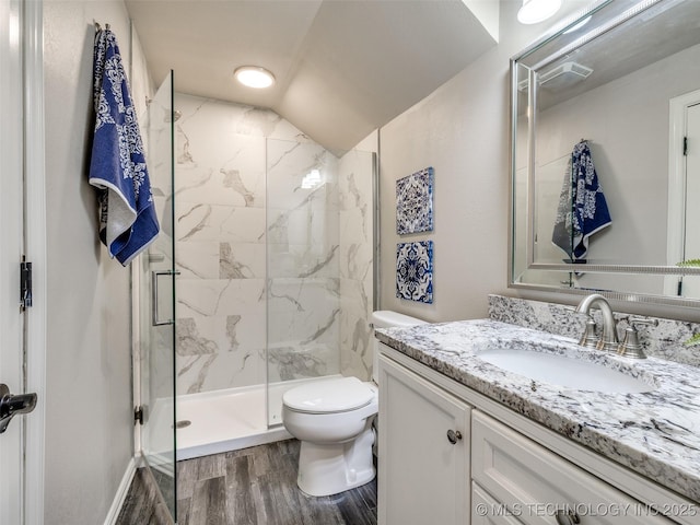 bathroom featuring vaulted ceiling, a shower with shower door, wood-type flooring, vanity, and toilet