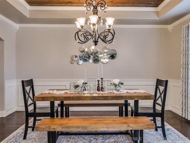 dining space featuring crown molding, dark wood-type flooring, a raised ceiling, and a chandelier