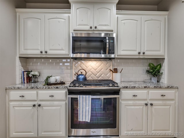 kitchen featuring tasteful backsplash, light stone counters, white cabinets, and appliances with stainless steel finishes