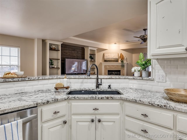 kitchen with tasteful backsplash, white cabinetry, sink, stainless steel dishwasher, and ceiling fan