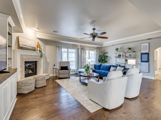 living room with ceiling fan, dark hardwood / wood-style floors, a raised ceiling, and a tile fireplace