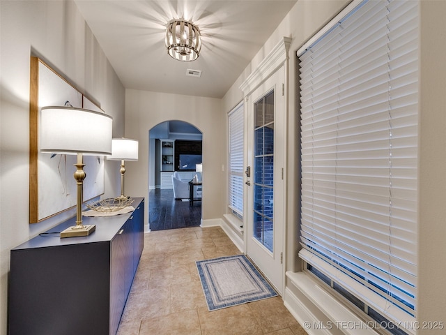 corridor featuring light tile patterned flooring and a notable chandelier