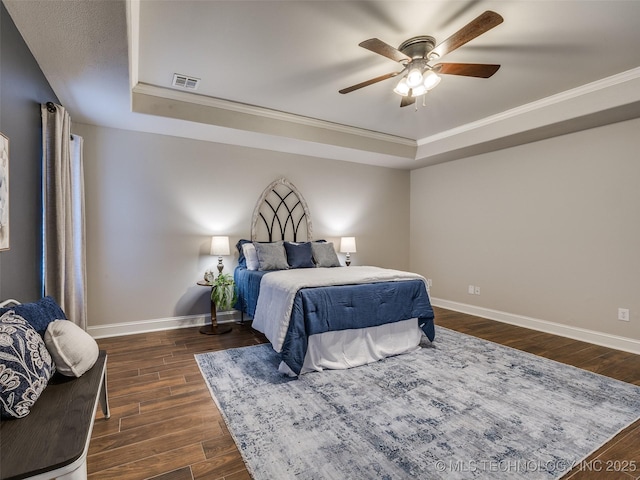 bedroom featuring a raised ceiling, crown molding, dark wood-type flooring, and ceiling fan