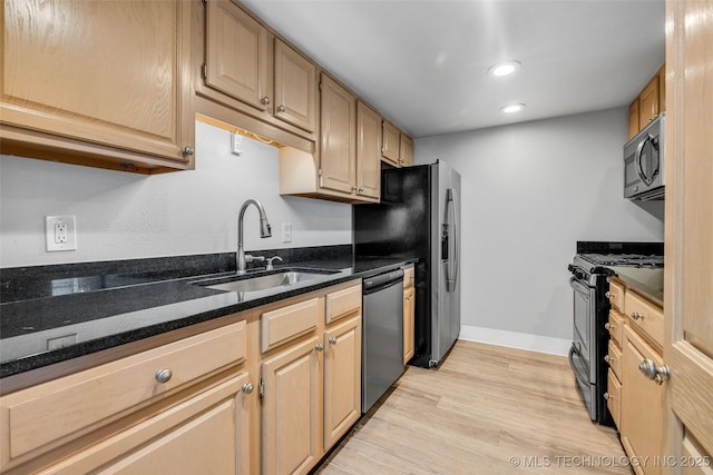 kitchen featuring light brown cabinetry, sink, light hardwood / wood-style flooring, appliances with stainless steel finishes, and dark stone counters