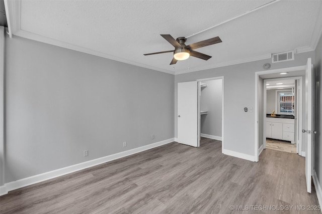 unfurnished bedroom featuring ornamental molding, ceiling fan, light wood-type flooring, and a closet