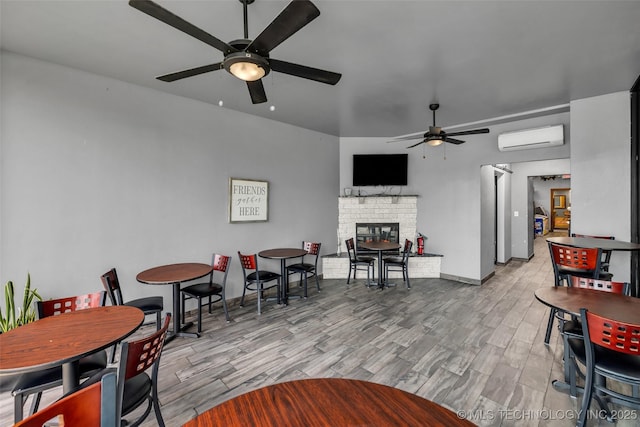 living room featuring an AC wall unit, light hardwood / wood-style floors, and a brick fireplace