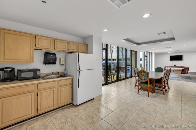 kitchen with sink, floor to ceiling windows, a tray ceiling, light brown cabinetry, and white fridge