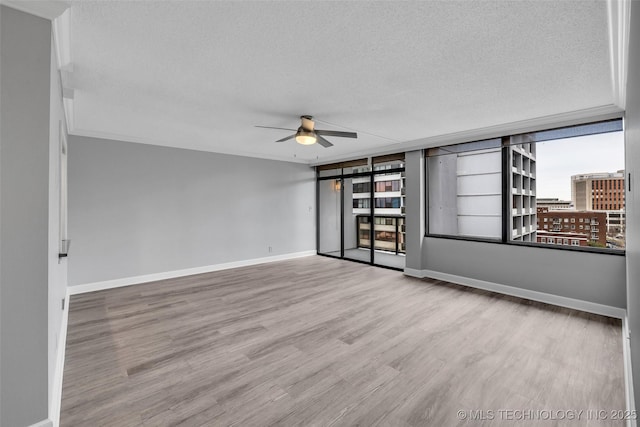 empty room featuring crown molding, ceiling fan, light hardwood / wood-style floors, and a textured ceiling