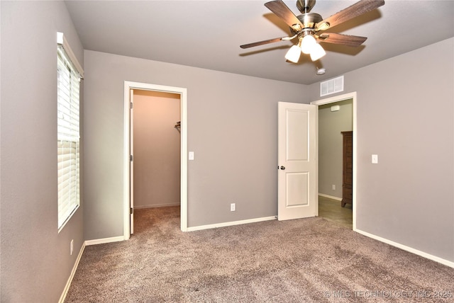 unfurnished bedroom with a walk in closet, carpet flooring, ceiling fan, and a closet