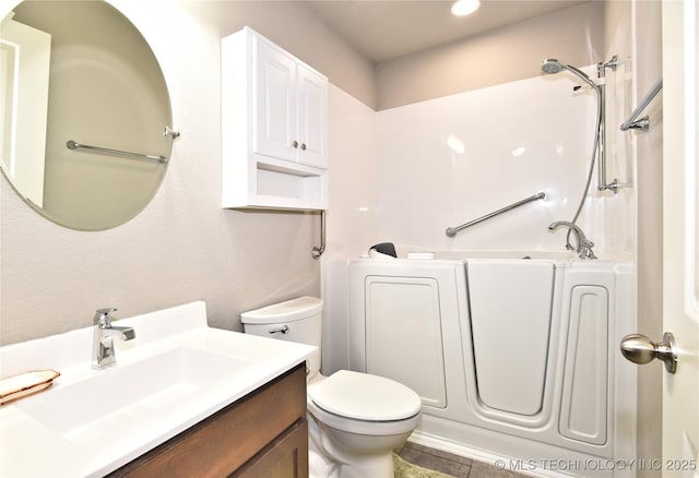 bathroom featuring vanity, a washtub, and toilet