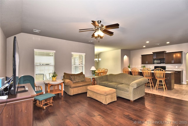 living room featuring lofted ceiling, ceiling fan with notable chandelier, and dark hardwood / wood-style floors