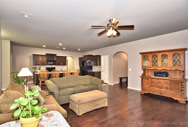 living room featuring dark wood-type flooring and ceiling fan