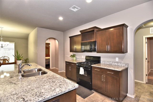 kitchen featuring light stone counters, dark brown cabinetry, sink, and black appliances