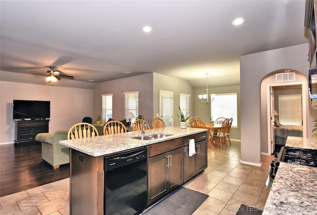 kitchen featuring sink, dark brown cabinets, black appliances, a center island with sink, and decorative light fixtures