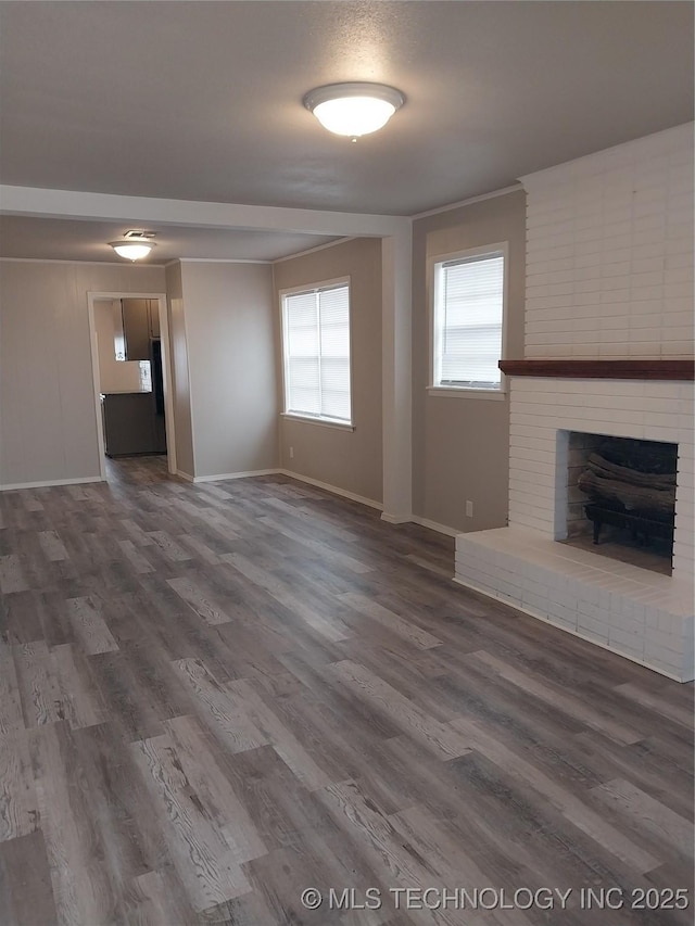 unfurnished living room with dark hardwood / wood-style flooring and a brick fireplace