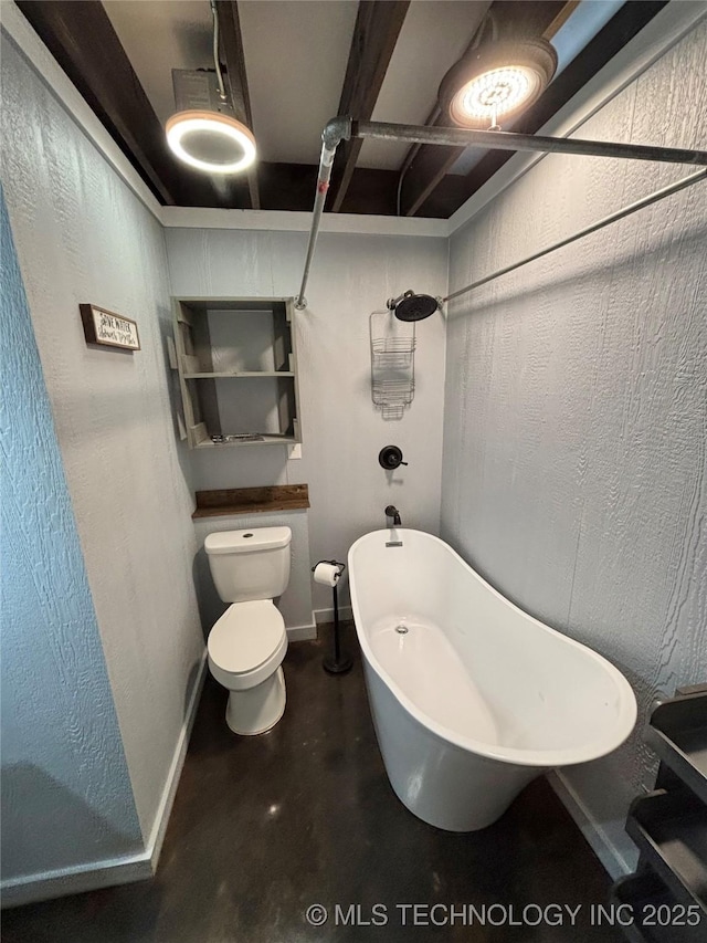 bathroom featuring a washtub, concrete floors, and toilet