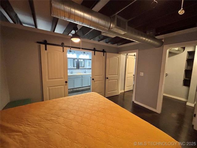 unfurnished bedroom with wood-type flooring, a barn door, and sink