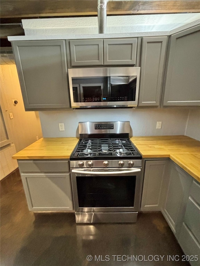 kitchen with wood counters, appliances with stainless steel finishes, and gray cabinetry