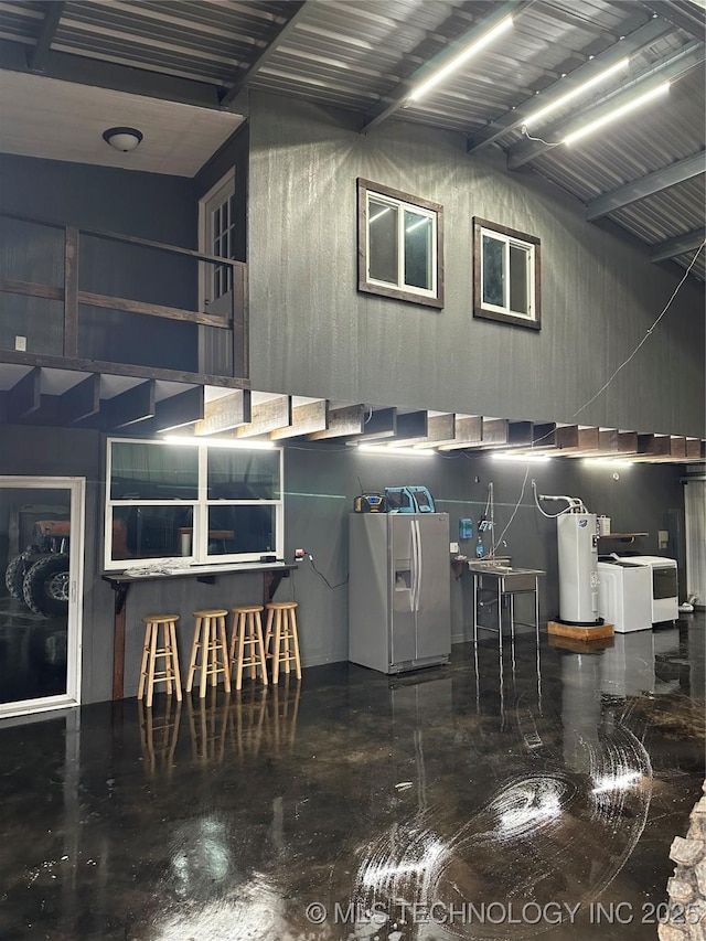 interior space with water heater, washer / dryer, vaulted ceiling, and white fridge with ice dispenser