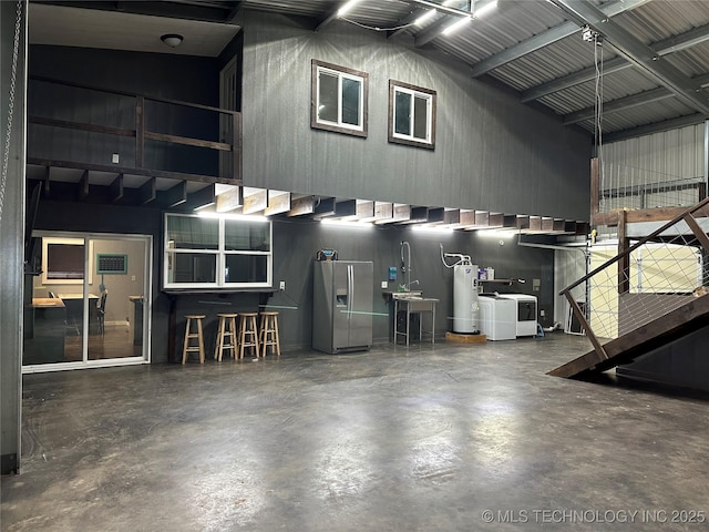 garage with separate washer and dryer, stainless steel fridge with ice dispenser, and water heater