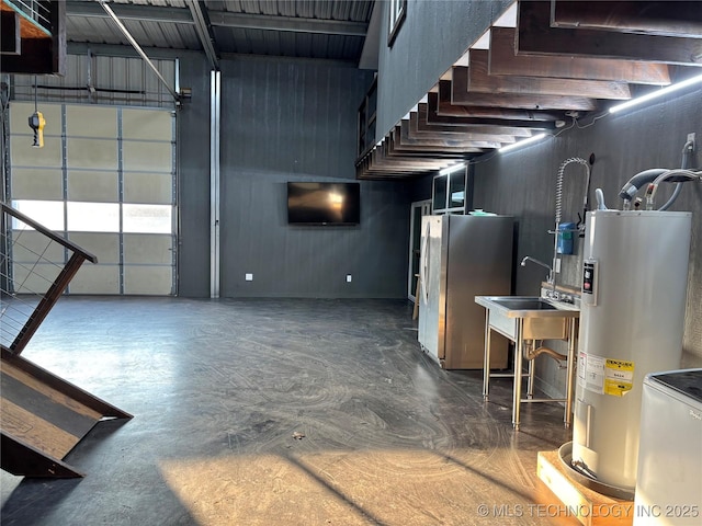 garage featuring water heater, sink, and stainless steel refrigerator