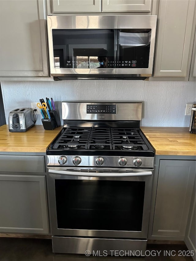 kitchen with butcher block counters, gray cabinetry, and appliances with stainless steel finishes