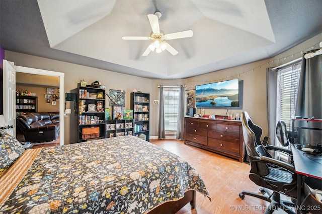 bedroom with multiple windows, a raised ceiling, and ceiling fan