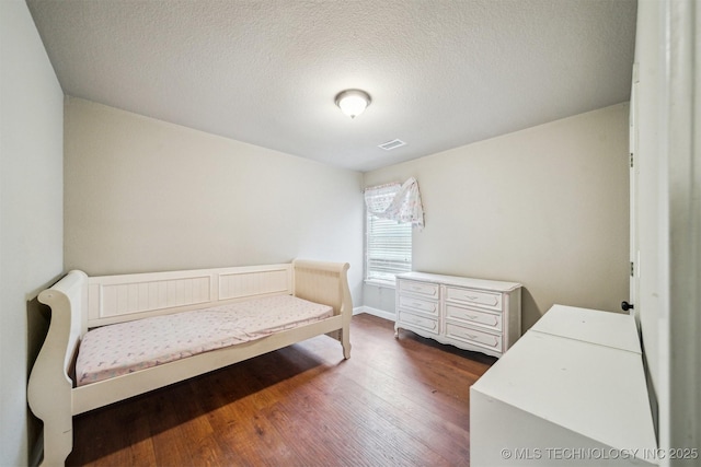 bedroom featuring dark hardwood / wood-style flooring and a textured ceiling