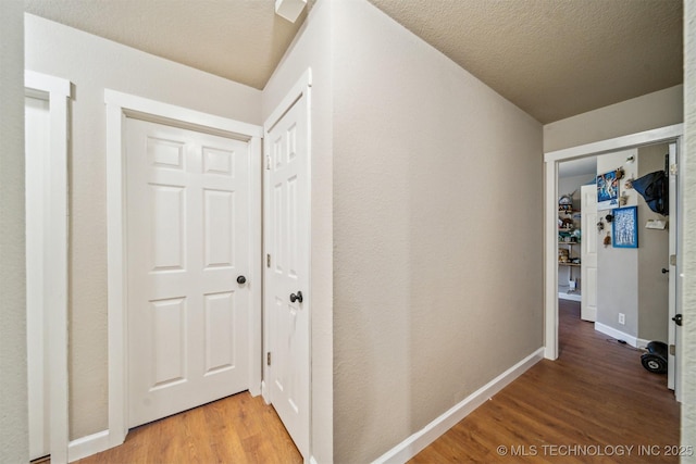 hallway with wood-type flooring and a textured ceiling