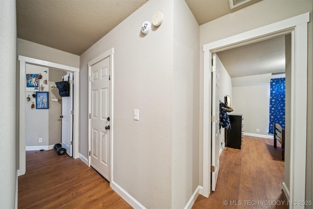 hall with hardwood / wood-style floors and a textured ceiling