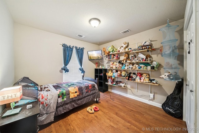 bedroom featuring hardwood / wood-style flooring and a textured ceiling