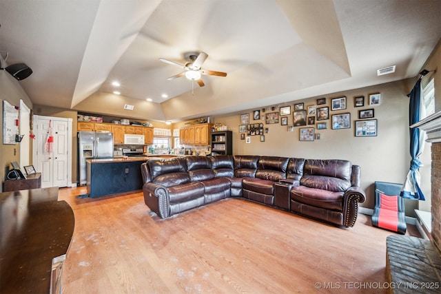 living room with ceiling fan, lofted ceiling, and light hardwood / wood-style floors