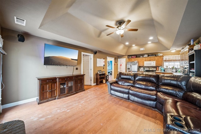 living room featuring vaulted ceiling, light hardwood / wood-style floors, and ceiling fan