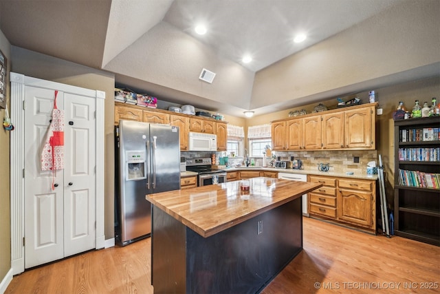 kitchen featuring lofted ceiling, butcher block counters, stainless steel appliances, light hardwood / wood-style floors, and a kitchen island