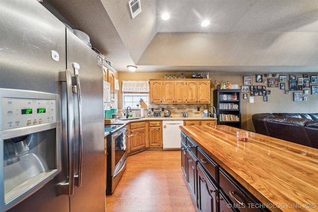 kitchen featuring wood counters, sink, appliances with stainless steel finishes, light hardwood / wood-style floors, and backsplash