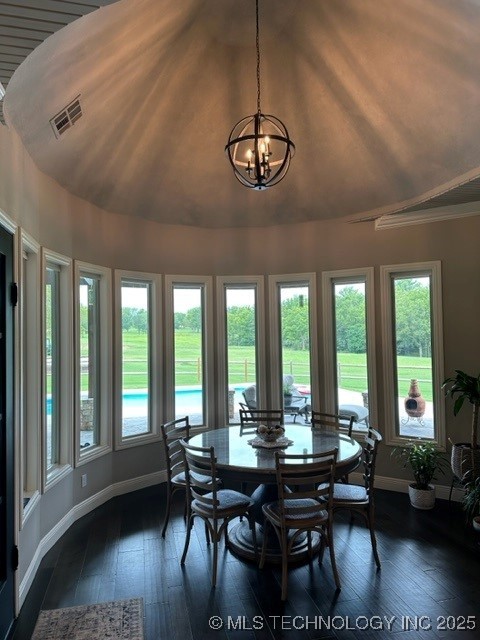 dining area featuring lofted ceiling, dark hardwood / wood-style floors, and a notable chandelier