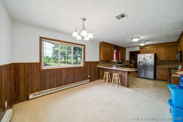 kitchen with baseboard heating, stainless steel appliances, kitchen peninsula, and hanging light fixtures