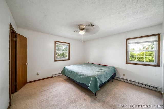 carpeted bedroom with multiple windows, a textured ceiling, and baseboard heating